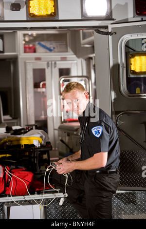 Männliche Rettungssanitäter mit medizinischen Geräten hinter Krankenwagen Stockfoto