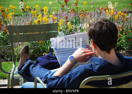 Mann liest Le Monde Zeitung im sonnigen Paris, Jardin du Luxembourg Paris Frankreich Stockfoto