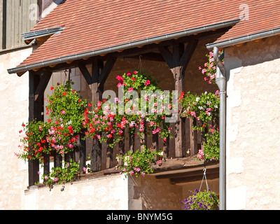 Hängende Körbe und Pflanzer auf Holzbalkon renoviertes Steinhaus - Frankreich. Stockfoto