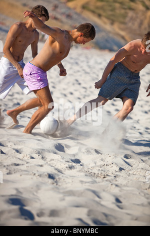 Junge Männer Fußball am Strand spielen. Stockfoto