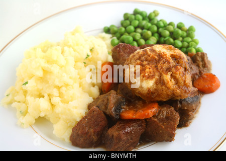 Traditionelle Rindsgulasch britische mit Knödel und serviert mit Petersilienkartoffeln Kartoffelpüree und Erbsen. Stockfoto