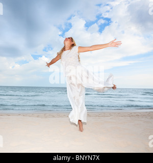 Junge Frau in weiß tanzen am Strand Stockfoto