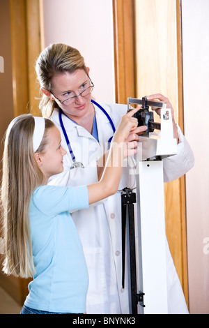 Arzt mit einem Gewicht von jungen Mädchen im Maßstab Stockfoto