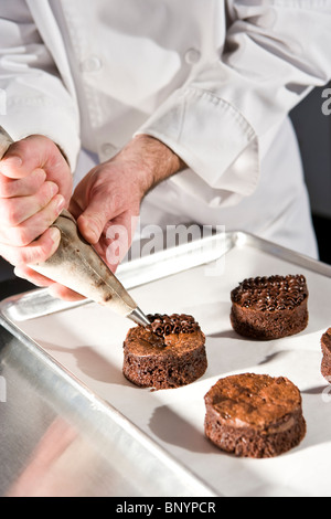 Ansicht eines Konditors dekorieren Schokoladendessert Gebäck beschnitten Stockfoto