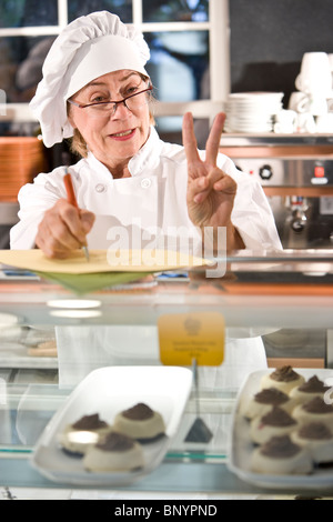 Baker unter Auftrag hinter Theke in Bäckerei Stockfoto