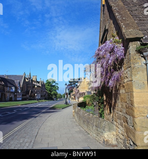 Broadway Dorf High Street, Cotswolds, Worcestershire, England, UK mit Wand ausgebildet Wisteria in voller Blüte Stockfoto