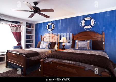 Kinderschlafzimmer mit zwei Betten, hölzerne Landhausmöbel Bücherregal und dekoriert mit Segelausrüstung Stockfoto