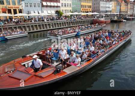 Nyhavn voll von überfüllten Canal Cruise Boote und Besucher und Touristen an der Wasserseite und Straßencafés Restaurants auf einem sehr warmen und langen Sommer Tag Stockfoto