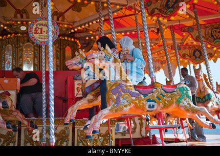 Mädchen in muslimischen Kopftuch, ein Betrieb einen Teddybär auf einem Jahrmarkt Karussell auf Brighton seafront Stockfoto