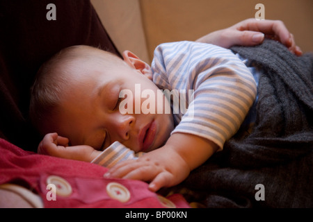 Baby Junge (16 Monate alt) schläft auf seiner Mutter Brust. Stockfoto