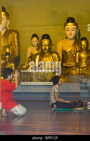 Pilger beten im Inneren kleine Pavillons mit Buddha-Statuen, Shwedagon-Pagode, Yangon, Myanmar Stockfoto