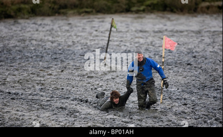 Ein Konkurrent wird während des Rennens Maldon Schlamm aus dem Schlamm gezogen. Bild von James Boardman Stockfoto