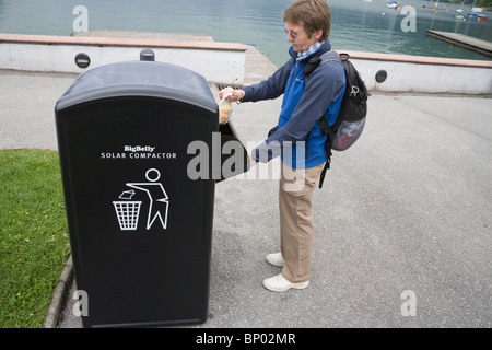 Europa-Frau setzen eine Tasche von Müll in das Fach des Big Belly Solar powered Wurf Müllpresse Stockfoto