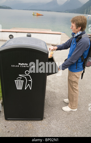 Europa-Frau setzen eine Tasche von Müll in das Fach des Big Belly Solar powered Wurf Müllpresse Stockfoto