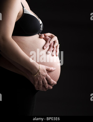 Schuss der Mutter und des Vaters Hände unterstützen schwangere Bump Stockfoto