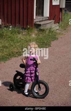 Kleines Mädchen Kleinkind im Party-Kleidung gekleidet sitzen auf einem Fahrrad Modell veröffentlicht Stockfoto