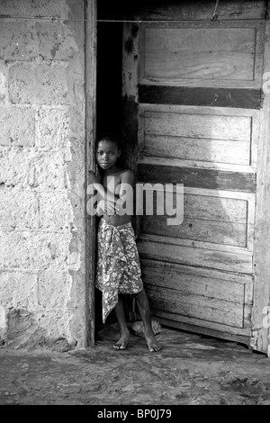 Mosambik, Ihla de Moçambique, Stone Town. Ein junges Mädchen in einem verschlissenen, alten Eingang ihres Hauses in Stone Town. Stockfoto