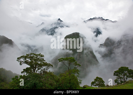 Peru, In den frühen Morgenstunden geringer Nebel und Wolken steigen aus den steilen Tälern rund um die Inka-Ruinen in Machu Picchu. Stockfoto