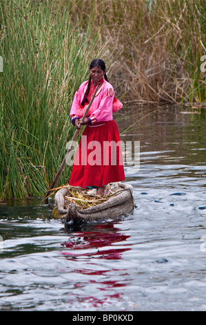 Peru, ein Mädchen von Uros Polen ihr Reed Kanu entlang eines Kanals zwischen den einzigartigen schwimmenden Inseln des Titicacasees. Stockfoto