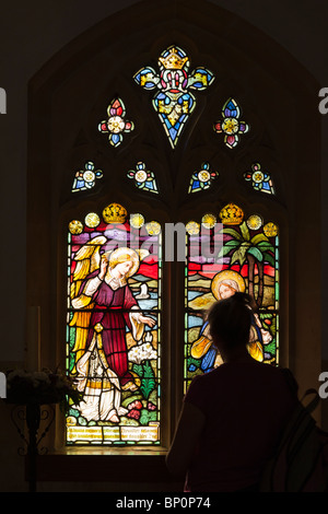 Frau betrachten Glasfenster in einer englischen Dorfkirche Stockfoto