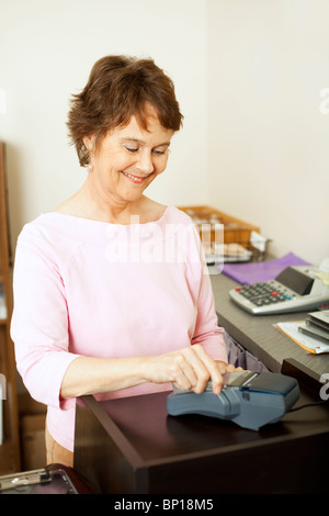 Verkäuferin läuft die Kreditkarte des Kunden durch das Terminal. Stockfoto