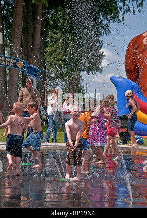 Diese vertikale redaktionelle stock Foto sind niedliche kleine Kinder spielen im Sommer in einem Brunnen mit vielen Wassertropfen. Stockfoto