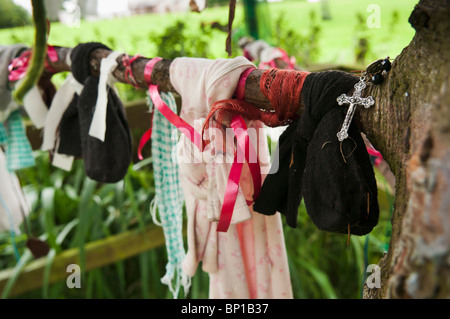 Bänder, Tuch und Geschenke hängen von den Zweigen eines Baumes am gut Heiligen Schrein für Saint Brigid von Kildare. Stockfoto