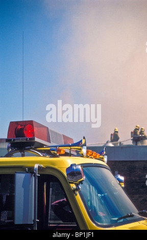 Feuerwehrleute am Dach des Feuers auf kommerziellen Baustelle Stockfoto