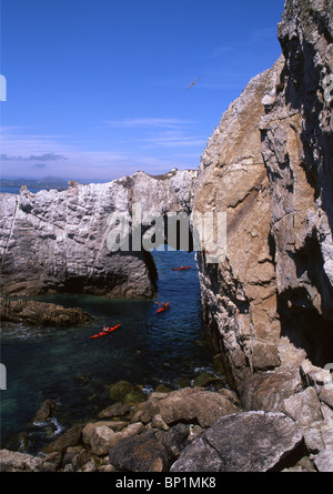 Meer-Kanuten paddeln unter Bwa Gwyn, natürlichen Felsbogen in der Nähe von Rhoscolyn Ynys Gybi Anglesey North Wales UK Stockfoto