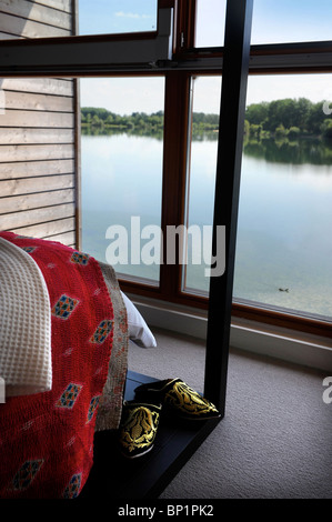 Schlafzimmer mit Blick auf einen See durch deckenhohe Fenster auf die "Zweitwohnung" Entwicklung - die Seen von Yoo in der Nähe von Cirences Stockfoto