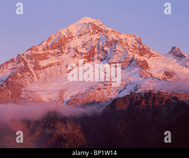 Sonnenuntergang rötet Neuschnee auf der Westseite des Mt. Hood und Strähnen von Nebel, Mt. Hood Wilderness, Mt. Hood National Forest, Oregon, USA Stockfoto