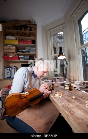 Eine klassische Violine Restaurator arbeitet auf einem Instrument in seiner Werkstatt, London, UK. Foto: Jeff Gilbert Stockfoto