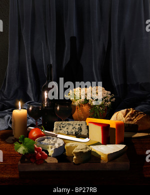 Vorstand der Käse mit Kräutern, Obst, Gemüse, Wein, Brot und Blumen in Kerze Kerze Stockfoto