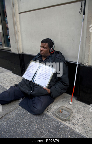 Blinder Mann mit Kopfhörern, Bettelei für Geld in Midtown Manhattan, New York City. Stockfoto