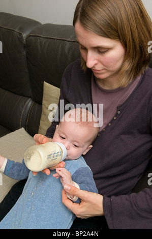 Eloi - 6 Monate - Essen aus seinem feed Flasche unterstützt durch seine Mutter Stockfoto