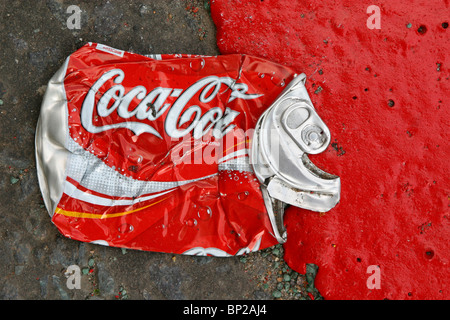 Eine Cola kann abgeflacht, in der Straße neben einem roten Route Straße Kennzeichnung in leuchtend rote Farbe, London, UK. Stockfoto