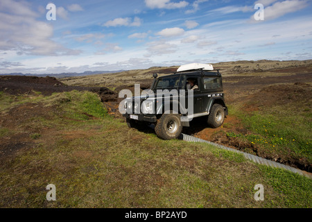 Land Rover Defender 90 300TDI navigiert einen gewaschenen Weg im Hochland von Island Stockfoto