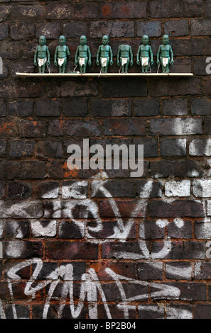 Kleinen grünen Figuren auf einem Regal 10 ft hoch auf der Innenseite einer Eisenbahn Brücke, London, Brick Lane. Stockfoto