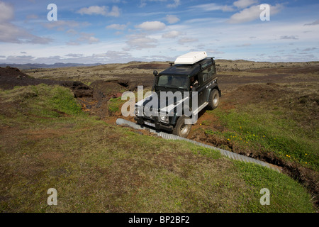 Land Rover Defender 90 300TDI navigiert einen gewaschenen Weg im Hochland von Island Stockfoto