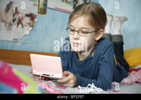 Ein Mädchen spielen Nintendo DS in ihrem Schlafzimmer Stockfoto