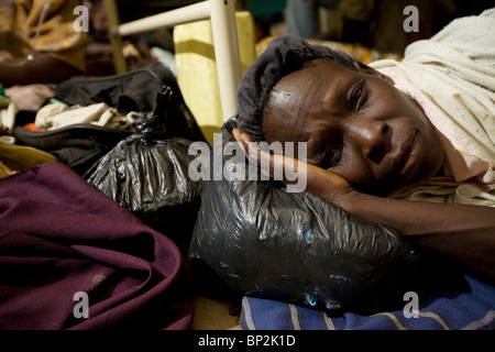 Eine Frau legt ihr Kopf auf eine Plastiktüte auf dem Boden eines überfüllten Krankenhauses in Amuria, NE Uganda, Ostafrika. Stockfoto