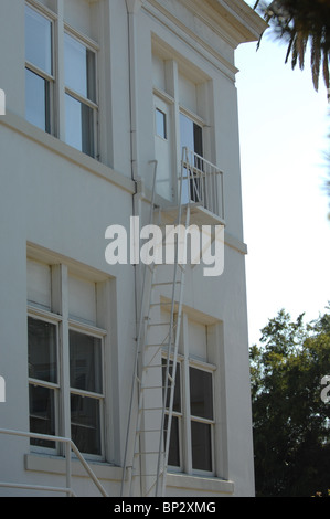 Notausgang Leiter und Treppe passend zur Seite eines sauberen weißen Gebäudes weiß lackiert. Stockfoto