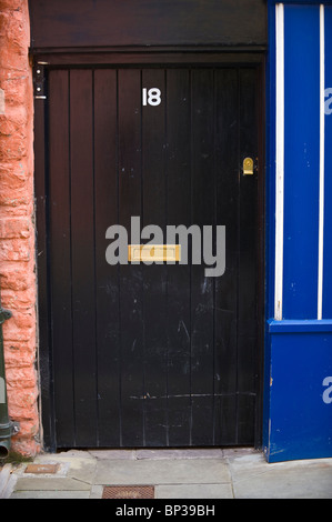 Schwarz bemalte hölzerne Haustür Nr. 18 mit Messing-Briefkasten des Hauses in UK Stockfoto