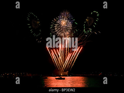 Multi farbige Feuerwerk ausbrechen in den Nachthimmel über dem Wasser Stockfoto