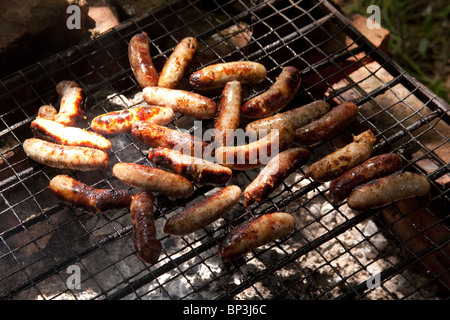 Würste Kochen auf ein Holzkohlefeuer oder zum Grillen. Hampshire, England, UK Stockfoto