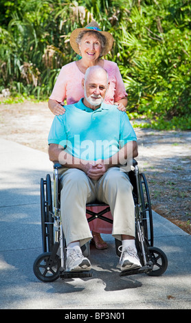 Ältere Dame drängen ihres Mannes in seinem Rollstuhl. Stockfoto