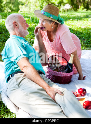 Romantische älteres Paar auf ein Picknick. Er füttert ihre Trauben. Stockfoto