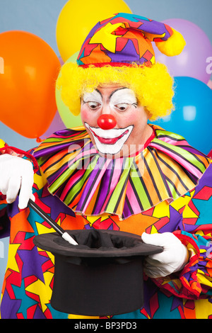 Geburtstag Clown eine magische Handlung mit einem Zylinder und Zauberstab. Stockfoto