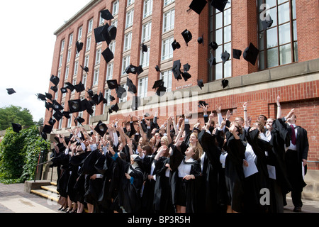 Absolventinnen und Absolventen jubeln und werfen ihre Hüte in die Luft für ein Foto nach einer Abschluss-Zeremonie an der University of Birmingham, UK Stockfoto