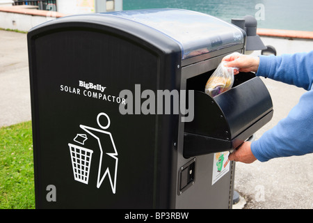 Person in einem BigBelly Solar angetriebene Verdichter Abfallbehälter für die Komprimierung von Müll Müll werfen Stockfoto